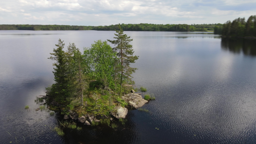 Green island in the middle of the lake, flying around, aerial view. The nature of Karelia and Finland.