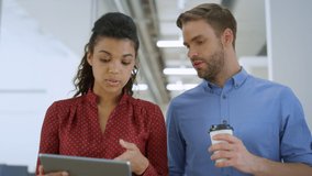 Closeup multiethnic colleagues talking while walking with tablet computer on modern office. African woman and caucasian man using digital device for work indoors. Business people discussing inside. - Powered by Shutterstock - Get 15% off with code: PIKWIZARD15