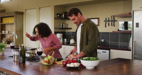 Happy diverse couple preparing food together in kitchen, chopping vegetables for salad. spending free time together at home.