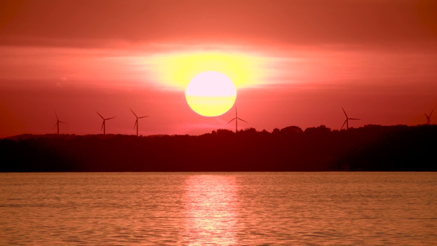 Sunset on a lake with wind turbines in the distance