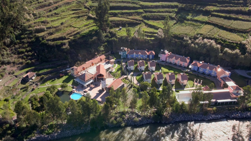Aerial clip of a hotel in Peru. It shows how incredible buildings can be in the middle of nature. The hotel looks like a small town next to the river.