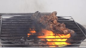 closeup of chicken pieces on the grill burning from high fire and strong smoke in daytime in 4k