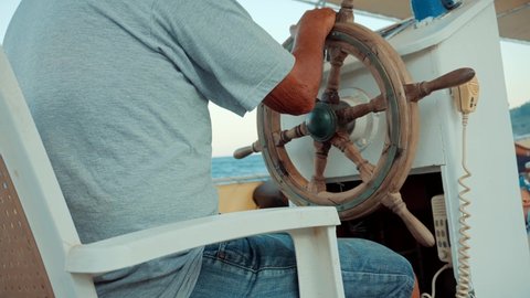 Steering Wheel On Sea Trips And Adventures Vessel.Captain Turns Wooden Steering Wheel On Ship.Fisherman Sailing On Sea And Looking Place For Fishing.Fishing Boat Floating Mediterranean Sea Turkey.