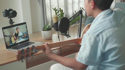 Boy Playing Guitar And Sing A Song While Streaming On Computer Laptop. The Children Is Broadcasting Live On The Internet
