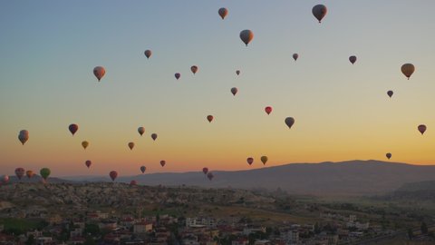 Goreme, Cappadocia, Turkey - May 30, 2021: Ballooning in Kapadokya. Many hot air balloons flying over spectacular breathtaking unusual valleys and rocks in blue sunrise morning sky