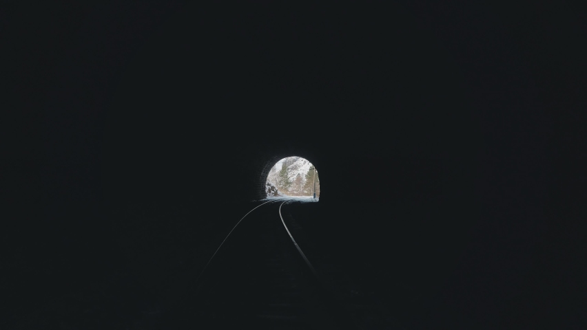 In first-person view train locomotive drives forward out of old dark arched stone tunnel. Winter snowy natural landscape ahead. Railroad travel. Abstract Russia Siberia Transsib railway. Baikal lake | Shutterstock HD Video #1074434666