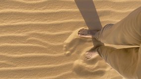 Vertical video. Slowmotion shot. A man walks on a dune in desert