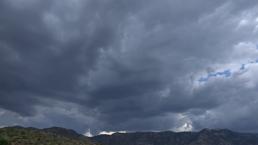Time Lapse, Storm clouds swoop in over mountains bringing veil of rain. 4K UHD 3840x2160