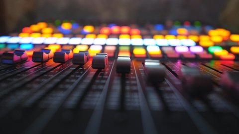 Low view of moving buttons on dj remote or soundboard. Working process in recording studio. Blurred background with brightly glow keys. Musical player at night party. Slow motion Close up