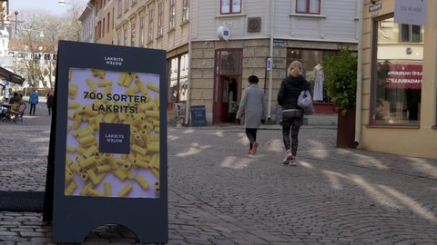 Gothenburg, Sweden - 04 28 2021: People crossing in front of a store sign in Haga, Gothenburg, Sweden.