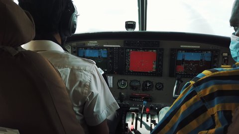 Zanzibar, Tanzania - 01 27 2021: View Behind African Pilots In The Cockpit Of Cessna Plane Flying Above Tanzania. medium shot