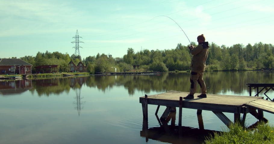 Man fishing on wooden pier near lake