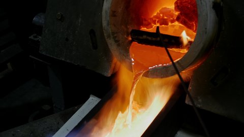 Liquid gold metal is pouring into industrial shape. Metallurgy. Torch blowing the fire. Precious Metal Industry. Gold Production. Fireproofed tools used in Complex of Gold metal manufacturing.Close up