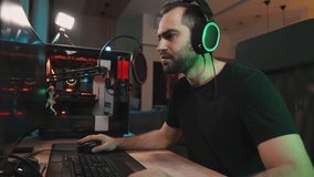 A displeased man gamer is loosing the game while playing on professional powerful computer sitting at home