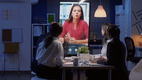 Diverse multi-ethnic businesspeople discussing management statistics during online videocall conference working in meeting office room late at night. Remote business manager solving company problem