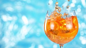 Super slow motion. Ice cube falling into glass of orange cocktail. Aperol spritz with sea surface background. - Powered by Shutterstock - Get 15% off with code: PIKWIZARD15