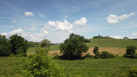 Countryside landscape view from the window of the train in Italy - hillside landscape with cultivated land - star a journey after finish of covid-19 Coronavirus lockdown - blue sky and clouds 