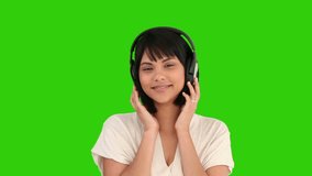 Chroma-key footage of a cute asian woman listening to music with an headphones