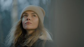 Close-up of a woman in a winter hat drinking hot tea from a mug on a cold autumn day, looking around pensively and sadly - Powered by Shutterstock - Get 15% off with code: PIKWIZARD15