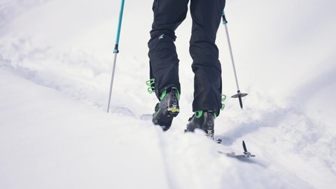 Samoens Refuge de Bostan, Haute Savoie, France - 02 15 2021: Close up view of skier walking uphill with poles in a snow landscape