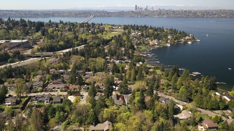 Cinematic 4K drone trucking clip of downtown Mercer island, Beaumont, Luther Burbank Park, residential and commercial areas, luxury, beachfront homes by Lake Washington, with Seattle in the background