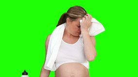Pregnant woman drinking water after sport against a green screen