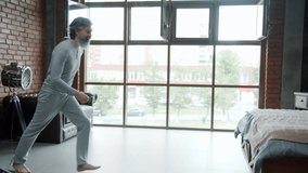 Slow motion of mature grey-haired man wearing pajamas jumping in bed at home enjoying rest alone. Relaxation and modern apartment interior concept. - Powered by Shutterstock - Get 15% off with code: PIKWIZARD15
