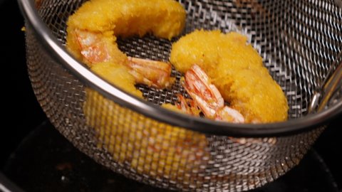 Cooking tempura shrimps in deep fryer. Closeup