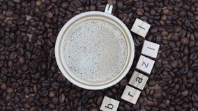 Top view of a cup of coffee on a background of coffee beans with the inscription Brazil. Vertical video