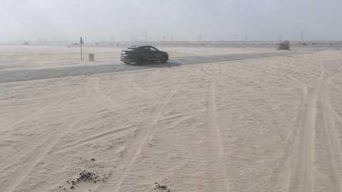 Dubai , United Arab Emirates - 11 15 2020: Black Lamborghini Urus driving on highway amid desert dunes in Dubai, side view
