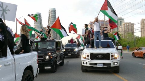 Mississauga , Canada - 05 18 2021: Demonstrators waving Palestinian flags standing on cars for pro-Palestinian rally in Mississauga organized by Palestinian Canadian Community Centre to create awarene