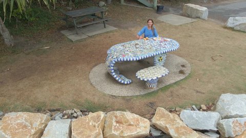 Woman Sitting By The Whale Table Mosaic Waves On Drone Camera Flying Away. Scotts Head In New South Wales, Australia. aerial