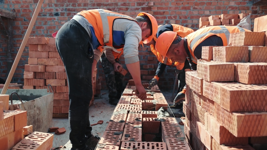 Builders building a brick wall. Construction work on construction. The masters lay bricks and build the wall of the house. Royalty-Free Stock Footage #1074520832