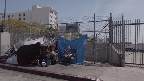 Los Angeles, CA USA - April 10, 2021: African American man in a wheelchair beside a tent in skid row
