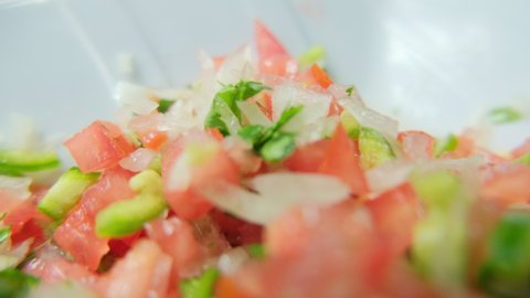 Close-up of chopped tomato, onion, green chili pepper, and coriander on white plate. Fresh and spicy pico de gallo sauce on porcelain plate. Traditional Mexican cuisine