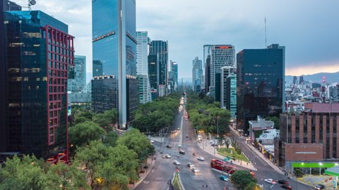 Aerial hyperlapse street view of busy urban traffic on multi lane road surrounded by tall modern skyscrapers in Mexico City