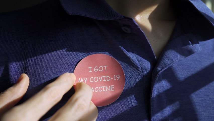 Attaching Covid-19 vaccine sticker on shirt