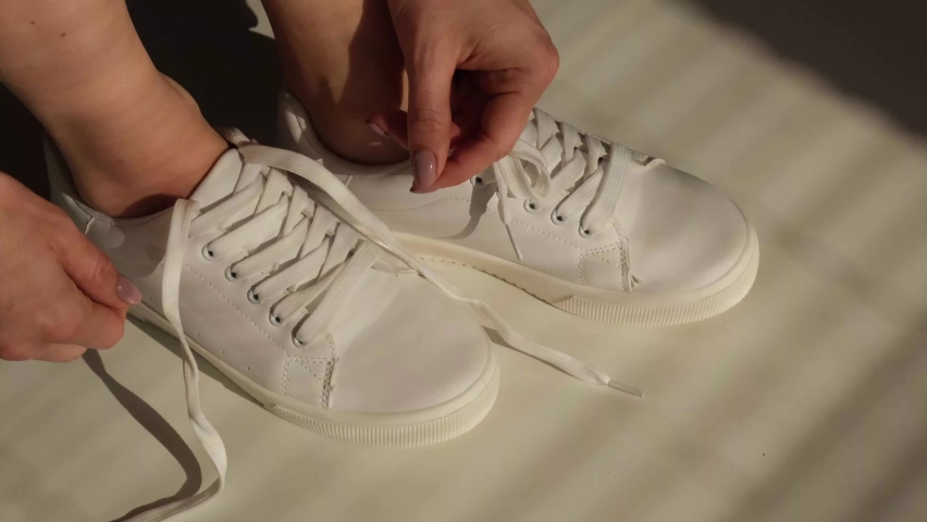 Woman put on new white leather sneakers