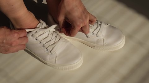 Woman put on new white leather sneakers