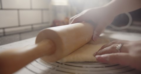 Slow motion Close up hands of bakery Chef preparing kneading roll out dough with a rolling pin on the table, Ingredients and preparation stages for cooking making bread cake at kitchen