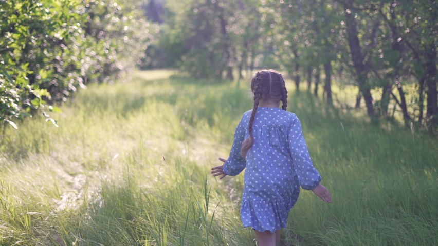 Happy girl. Little girl run through forest park. Kid plays on green grass. Happy kid run in garden. Green grass and trees in forest park. Little girl run through green garden.Happy girl among trees Royalty-Free Stock Footage #1074536828