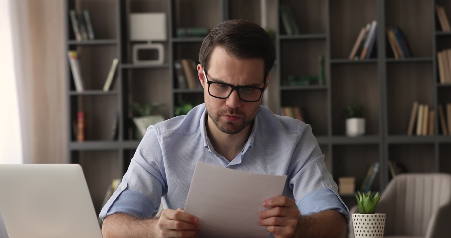 Angry stressed young businessman in eyeglasses sit at desk reading bad awful news in mail letter document about credit denial, bank debt, dismissal staff cuts notice high taxes need to pay concept Royalty-Free Stock Footage #1074542378