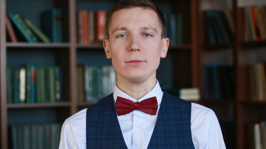 Happy white man standing in university library showing thumb up and smiling