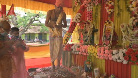 Howrah, West Bengal, India - 29th June 2020 : Hindu priest ending yajna after worshipping idol of God Jagannath, Balaram and Suvodra , in front of sacred fire with mantras, inside pandal..