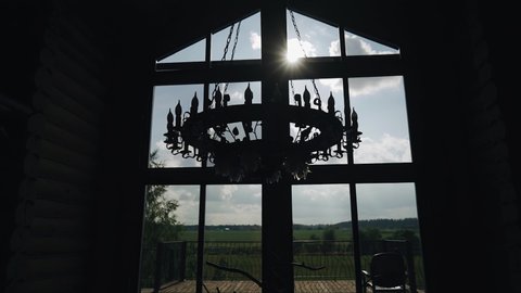 A beautiful chandelier hangs on the background of a bright window behind which you can see the sky and clouds. Wonderful shots in the nomination