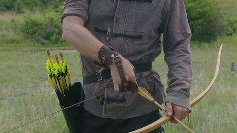 a young guy shoots a bow at a target, in nature, and hits the target, the arrow pierces the target for flight, pulls the bowstring tightly for a shot. Prores 422