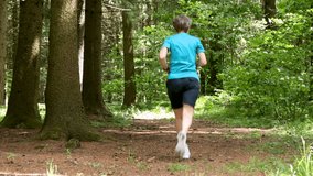 an adult woman runs alone in the forest on a sunny day.