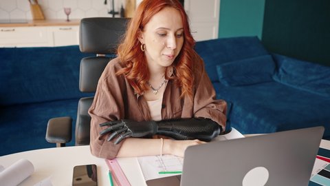 Freelance and remote work for people with disabilities. An interior designer girl with a prosthetic arm has a video call from her home office. Meeting with the customer.