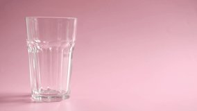 Milk is poured into a glass on a pink background.