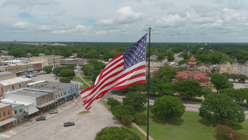 The American Flag flown in Gonzales Texas with the historic courthouse in the background.